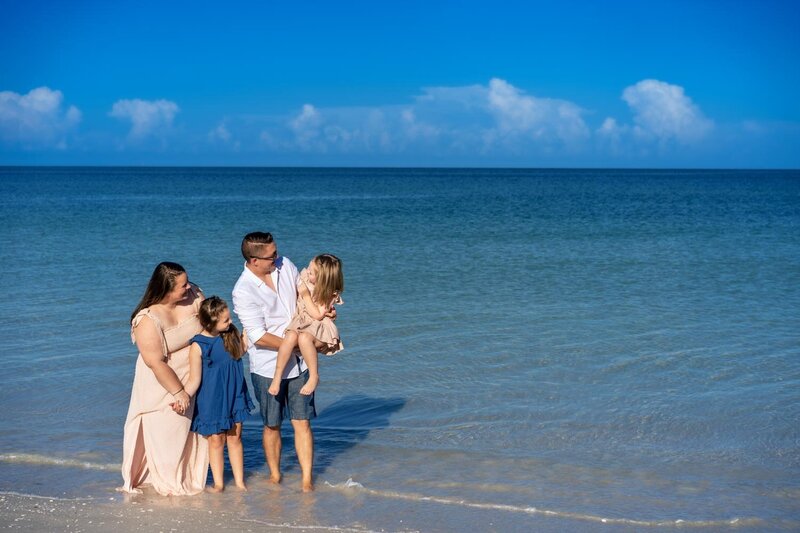 family standing in the water along the beach in florida