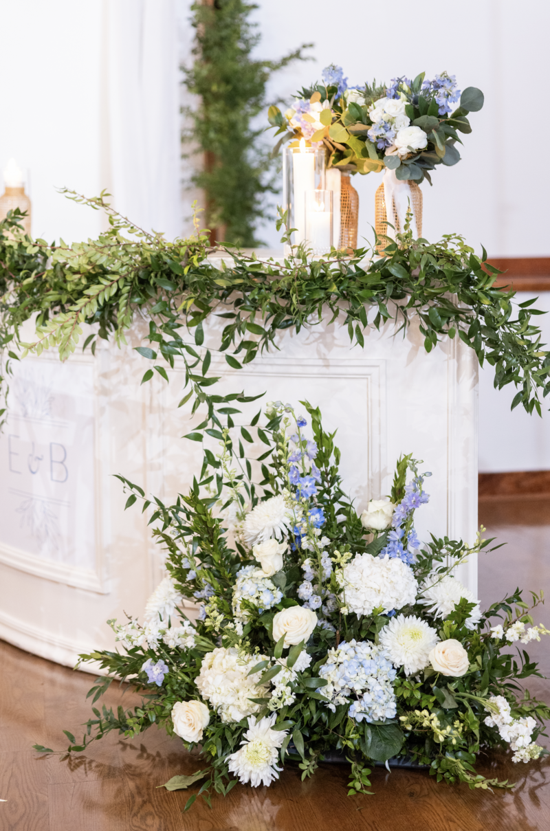 Spring wedding at WinMock at Kinderton, designed by Charming Carolina — custom bar featuring the couple’s monogram, greenery accents, and candles in the reception space.