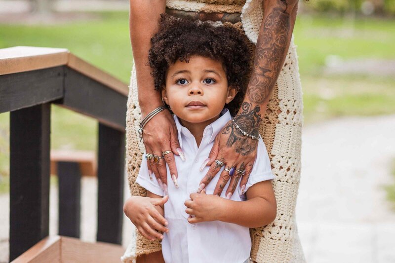 Closeup of toddler's face standing in front of his mom's legs