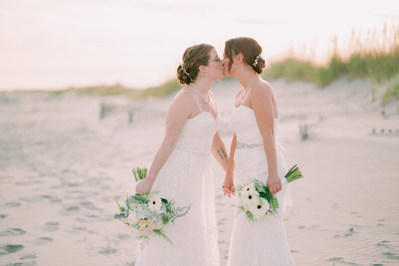 Newlyweds kiss one another, both in dresses, at Ocean City Beach.