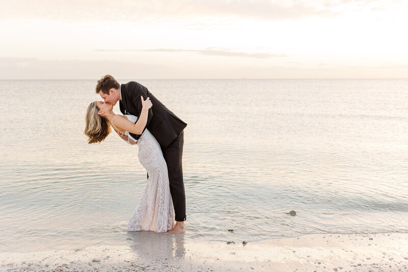 Bride and Groom sharing a dip kiss on the beach during sunset.  Photo taken by Meredith Mutza Photography LLC, located in Milwaukee, Wisconsin.
