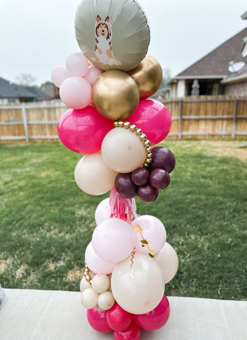 Crazy tower with pink, maroon and gold balloons and collie decoration.
