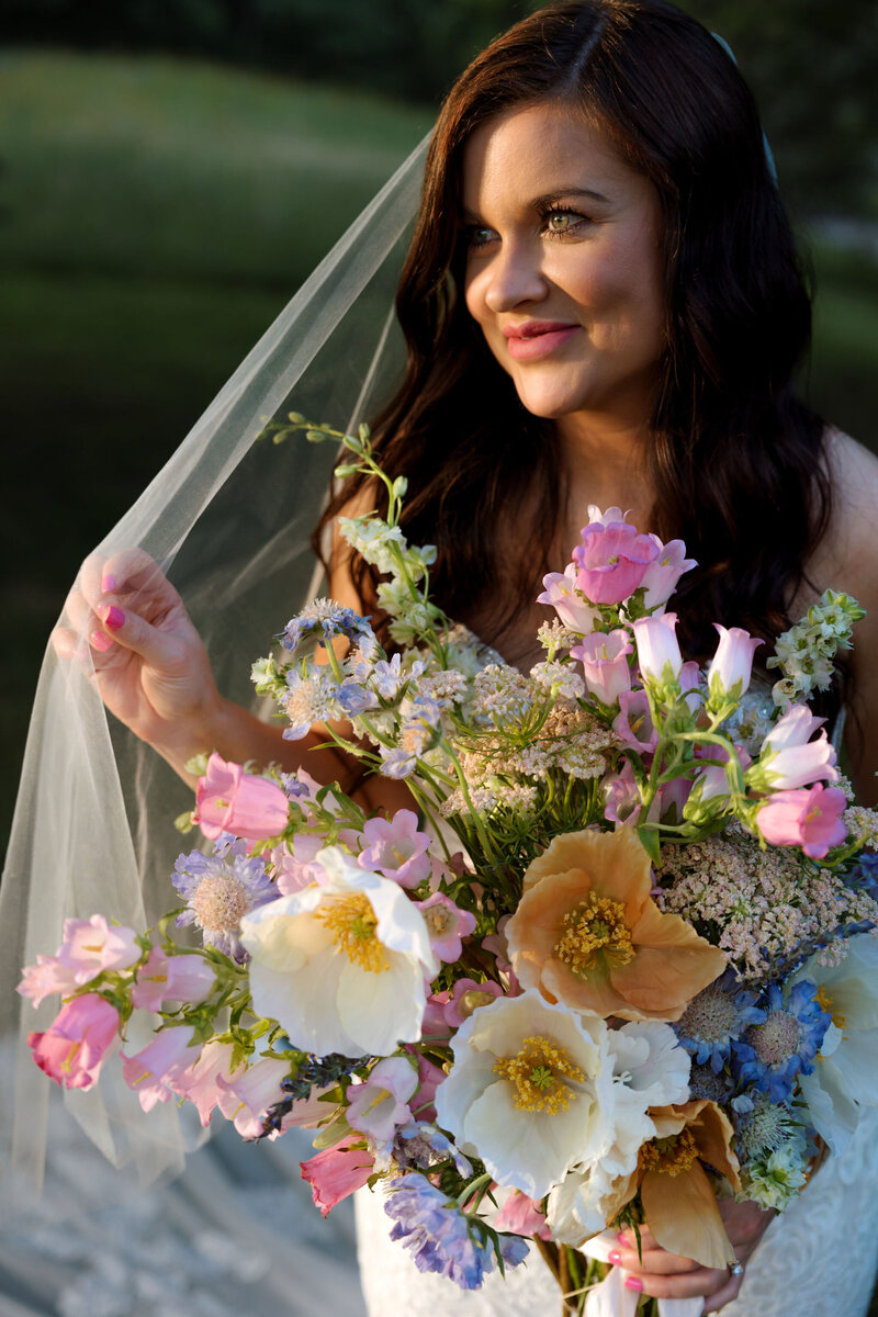 A Nashville bride holding a colorful bridal bouquet at an outdoor wedding in the summer