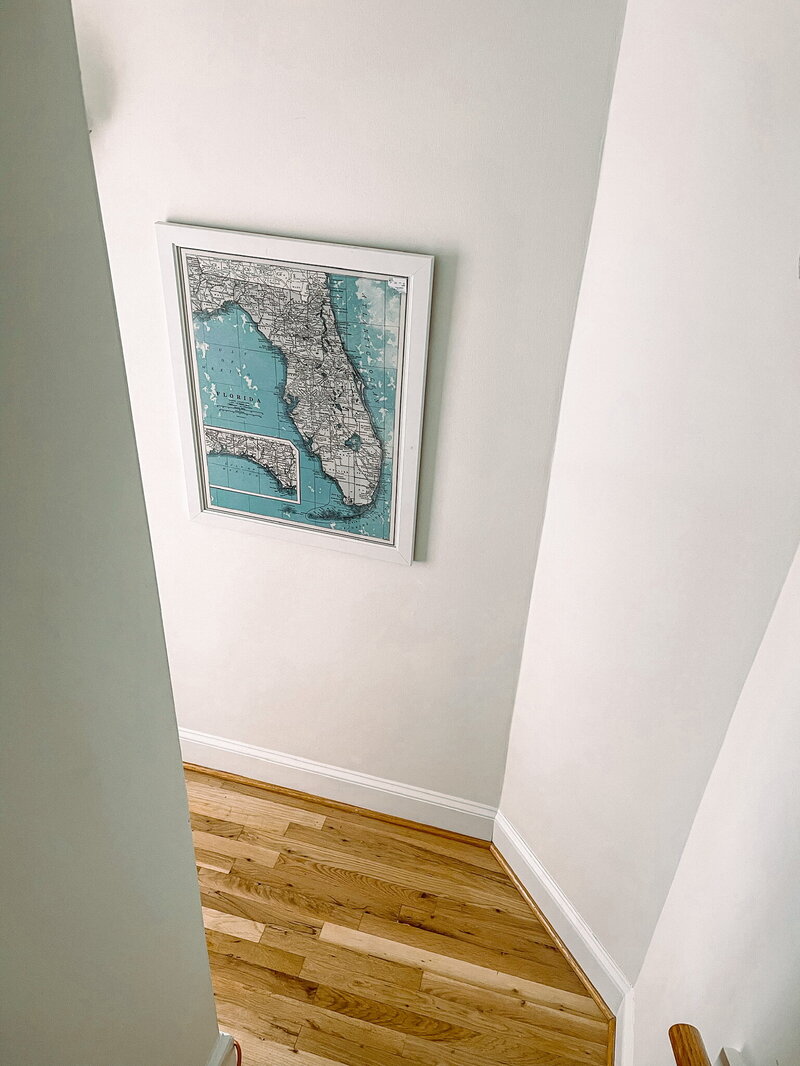 white stairwell with a map of florida hung on the wall