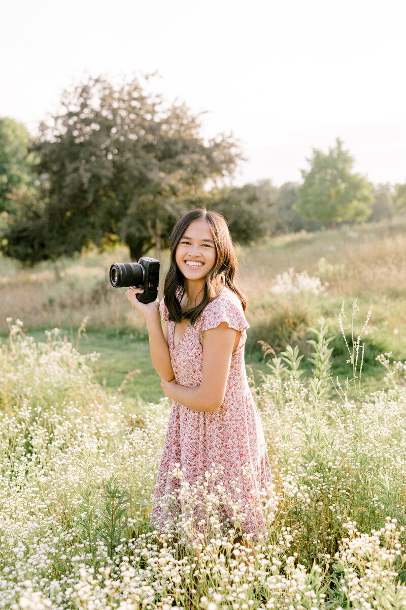 girl holding camera in a flower field laughing