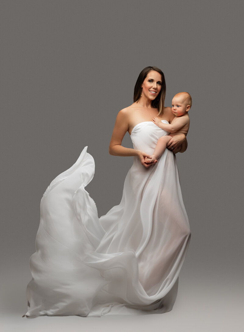 Motherhood portrait with mother looking down lovingly at daughter on her hip