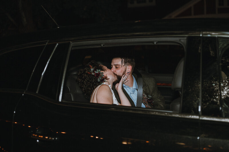 bride and groom kissing in car