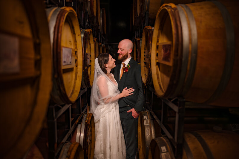 Couple embrace in between winer barrels at Chicago Winery