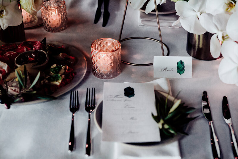 Dark green moody wedding reception with emerald green wedding menu and candles