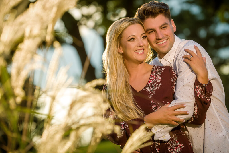An engaged couple sharing a tender embrace in the warm glow of a golden sunset during their engagement session, capturing a romantic and timeless moment.