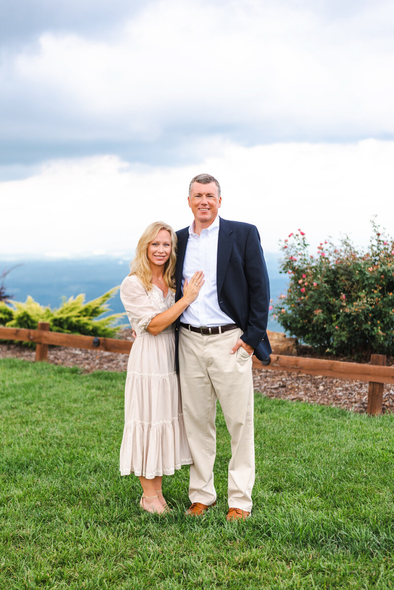 A portrait of David and Terri Parker, owners of Hidden Hill Venue. They are standing with the Blue Ridge Mountains behind them.