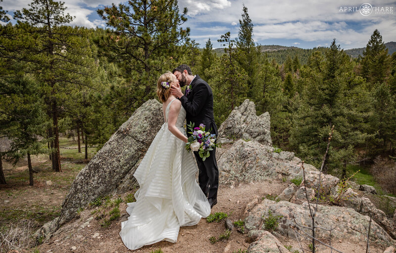 Couple Kiss at their First Look in the forest at The Woodlands Wedding Venue in Colorado