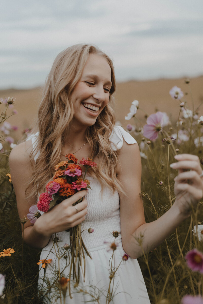 Blonde female in white dress laughing in flower field