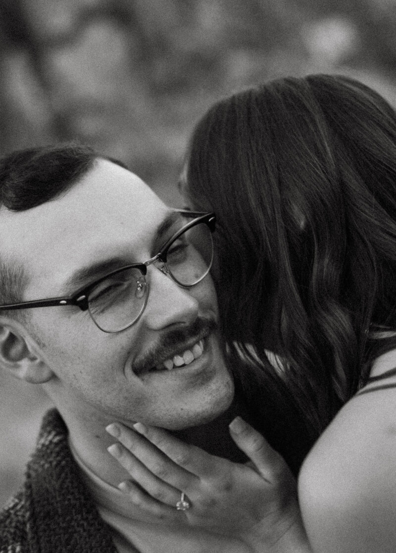 Candid moment of a woman whispering into her partner’s ear during a couple’s photo session in Oregon.
