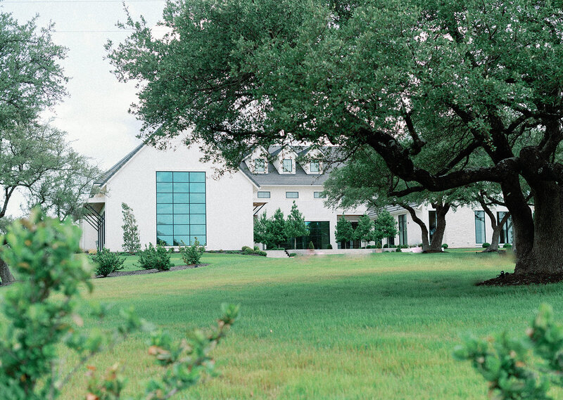 Exterior view of The Arlo wedding venue in Austin, featuring modern architecture and oak trees at sunset.