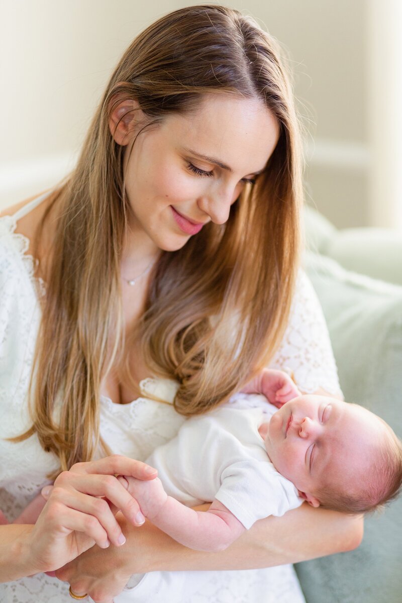 mom with long hair holds newborn in white onesie