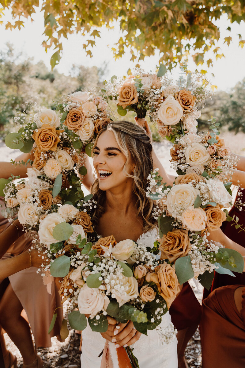 a bride laughing in the middle of a circle of flowers