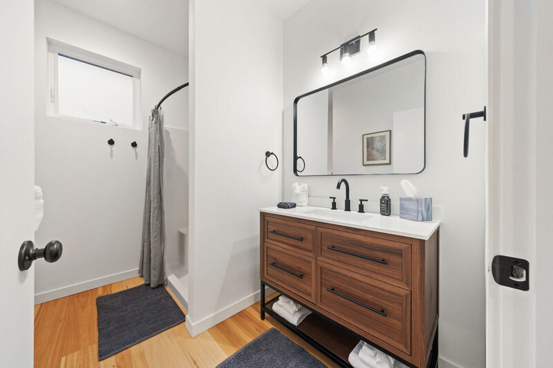 Sleek bathroom with wooden vanity, large mirror, and walk-in shower