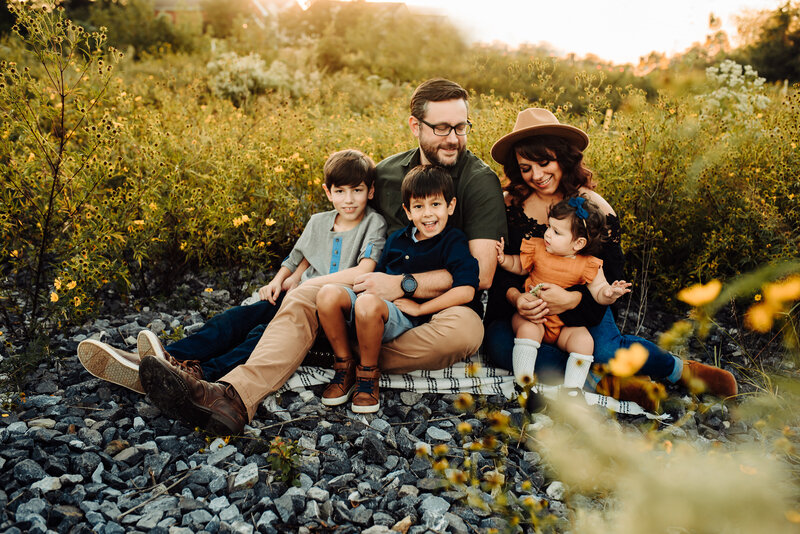 Family with two boys and one girl sitting in gravel and flower field near Washington DC