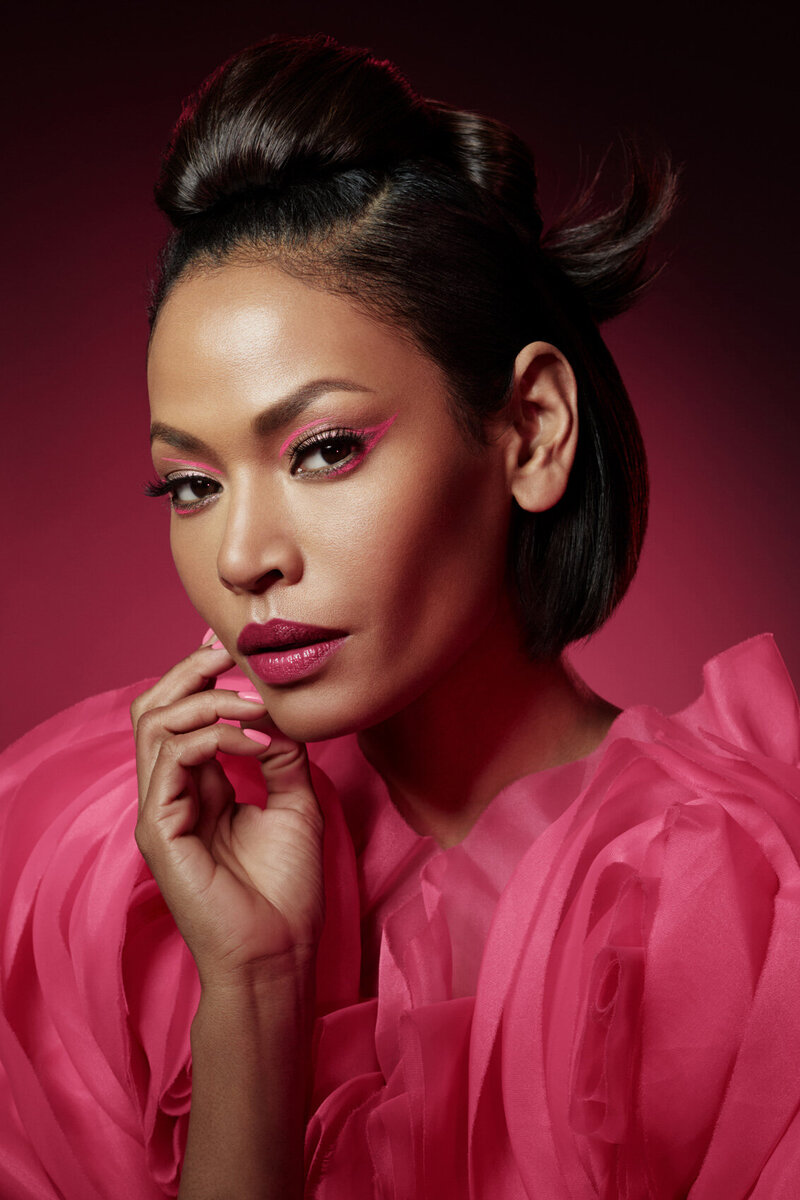 Confident portrait of Amira in a pink, textured outfit with defined makeup, captured by Ylva Erevall.
