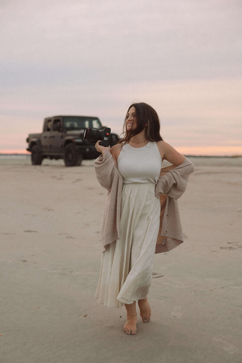commercial photographer standing on beach with camera smiling