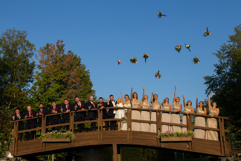 Wedding Party standing on bridge flowers in air | Sugarloaf Maine Wedding Photography