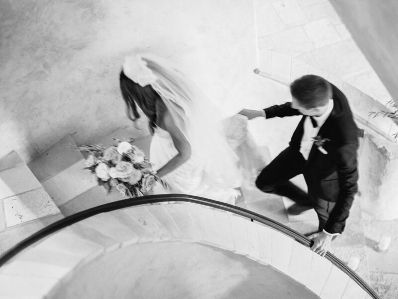 black and white image of wedding couple walking up staircase at sunstone winery and villa