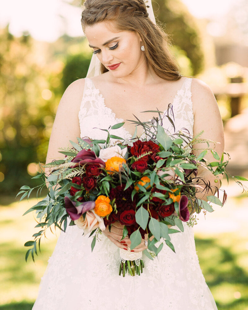 Bride holding vibrant bouquet with red and orange flowers