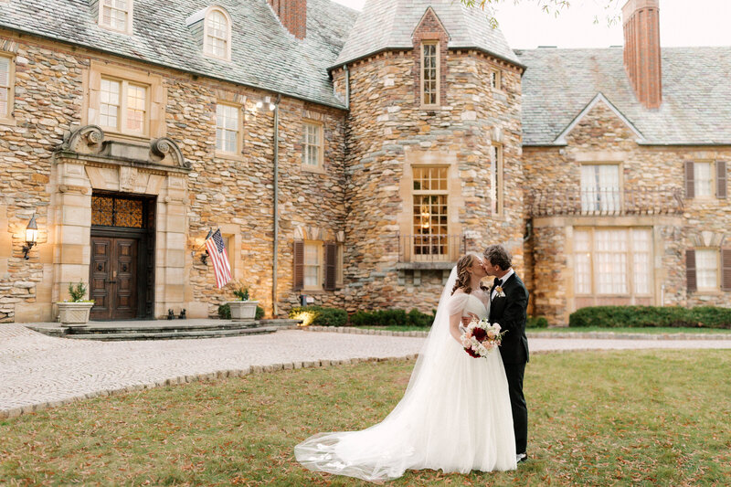 November wedding at Graylyn Estate, designed and planned by Charming Carolina — romantic sunset portrait of the bride and groom kissing in front of the historic stone manor house.