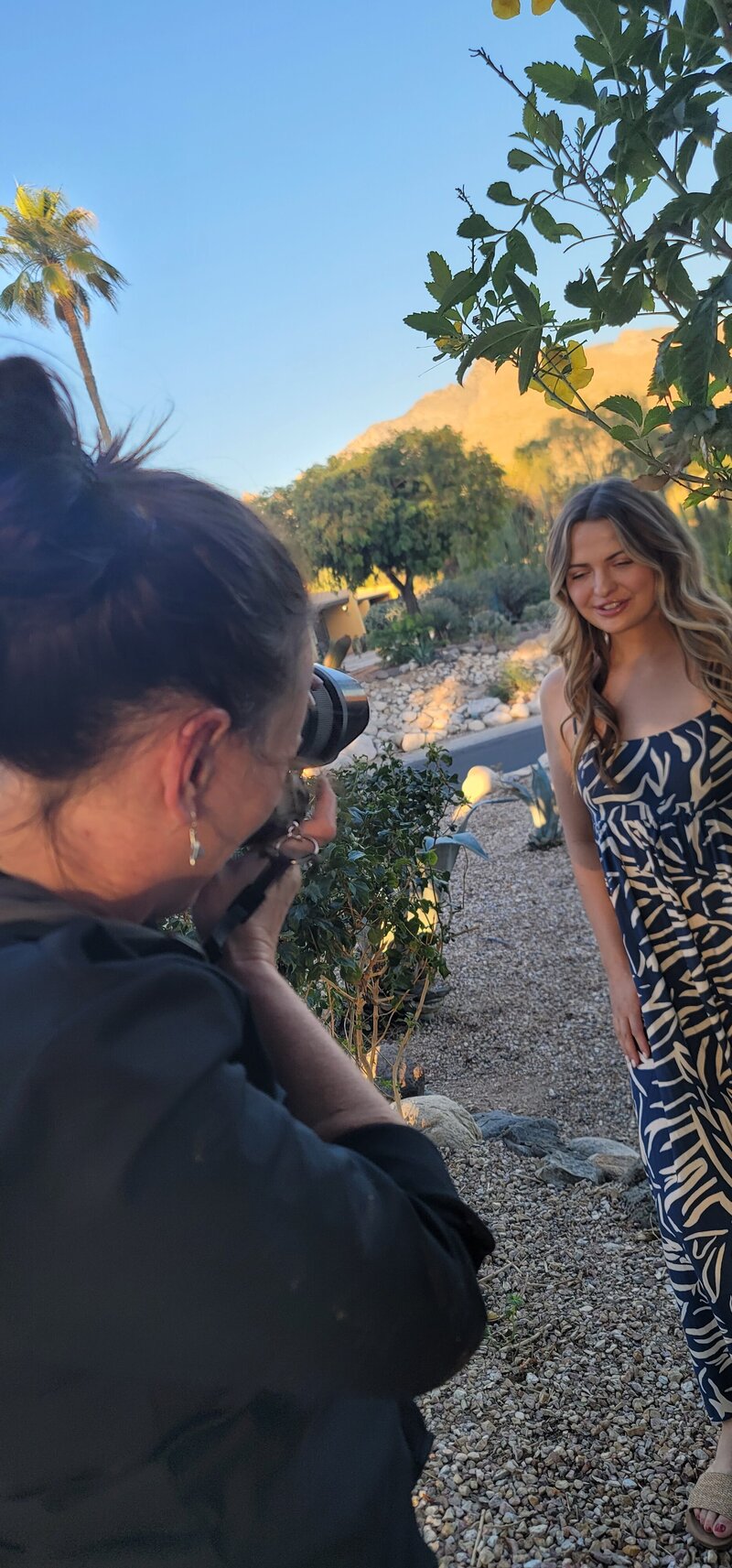 Photographer capturing a smiling woman in a patterned dress during a warm outdoor portrait session in Tucson, showcasing natural light brand photography by Vyrl Photo.
