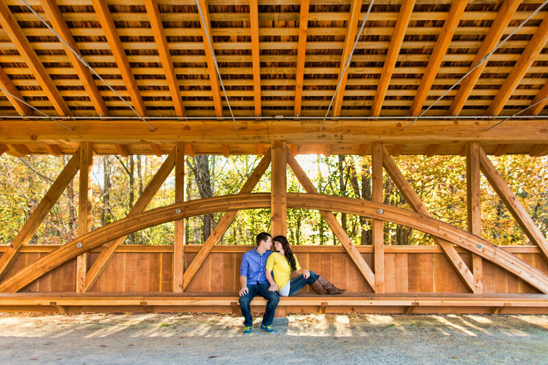 Couple sitting close together under a wooden structure, sharing a candid moment at Longwood Gardens.