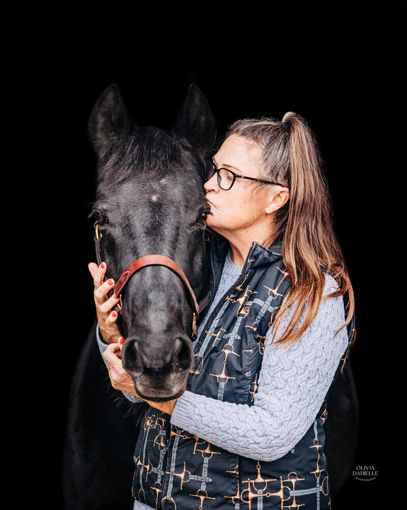 woman kissing her black horse
