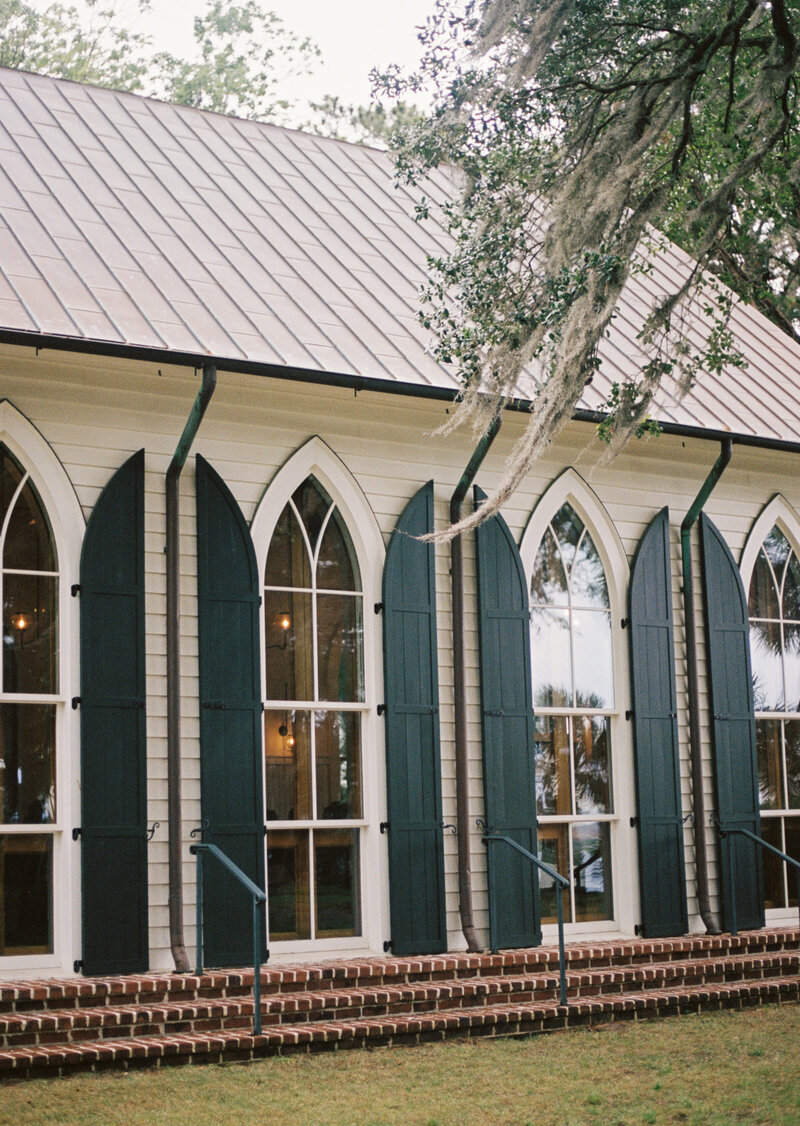 a wedding chapel with large windows and shutters surrounded by spanish moss trees in SC