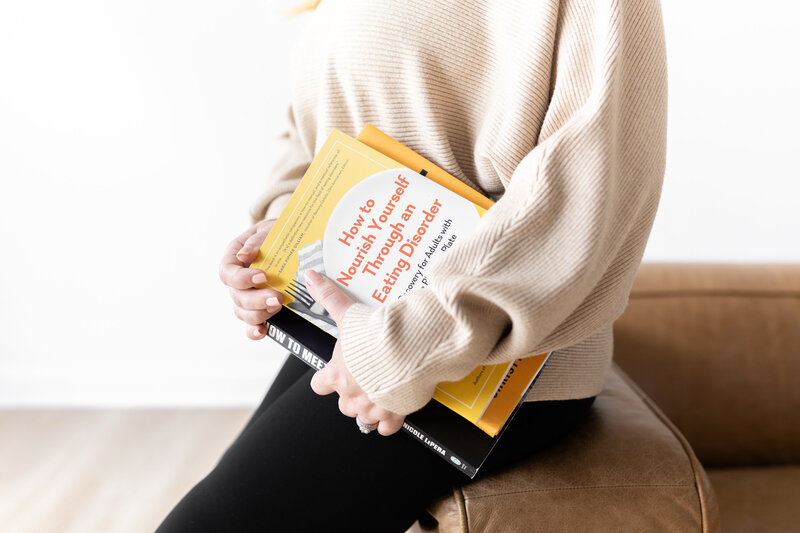 Person holding books about eating disorder recovery