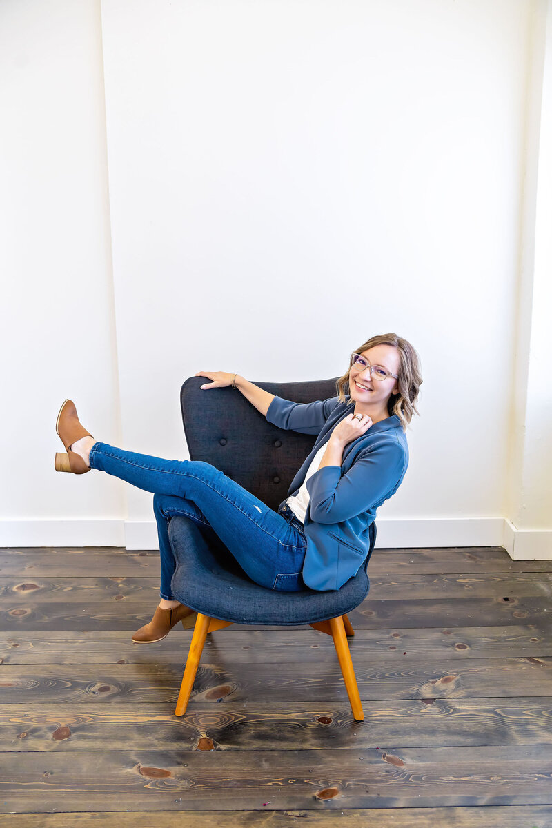 Elizabeth Rose, a certified holistic nurse and a craniosacral fascial therapist sitting happily on a chair, embodying balance, well-being, and holistic care.