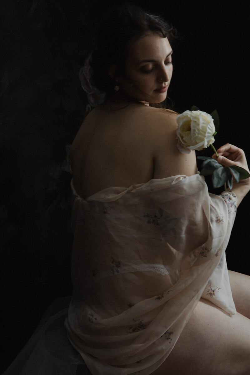 Donna con peonia bianca vicino al volto, sguardo chiuso e mosso – effetto etereo.