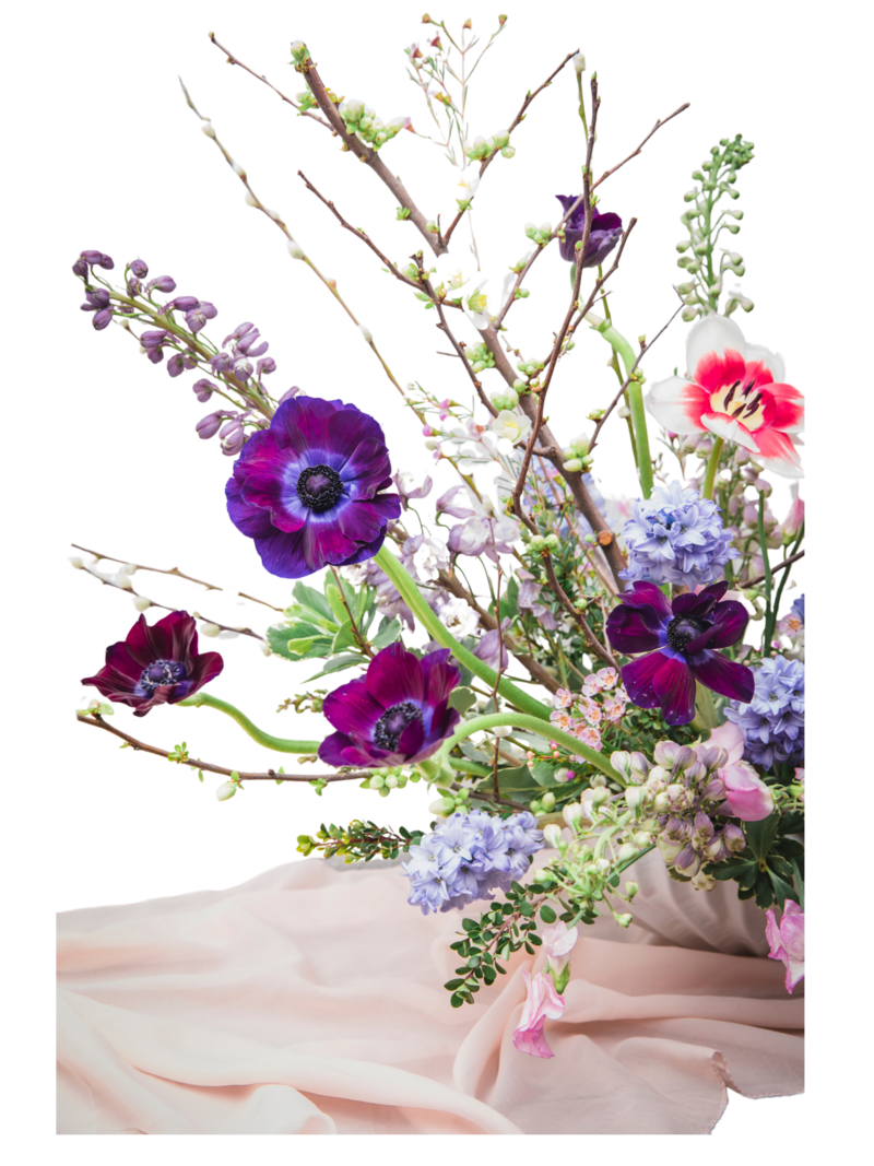 Floral arrangement with purple and pink flowers, on light fabric.