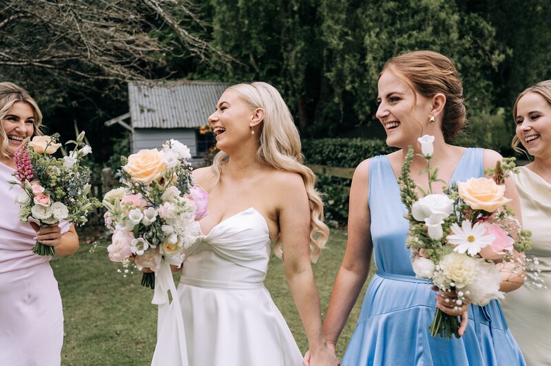 candid wedding photo of bride laughing with pastel flore studios bouquet near gore