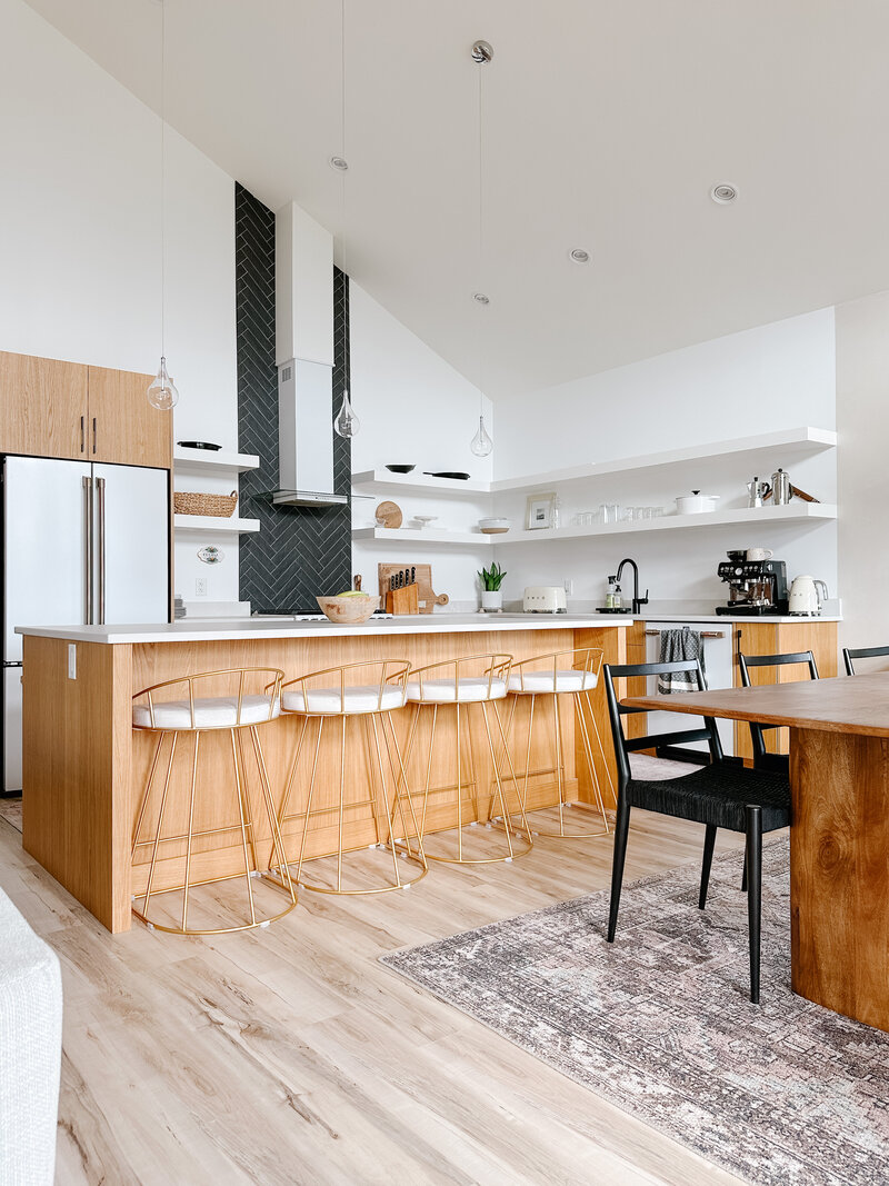 Interior Design of a kitchen by Hanbury Design Co. A modern, open concept kitchen design with high-ceilings, oak cabinets, pendant lighting, and cafe appliances.