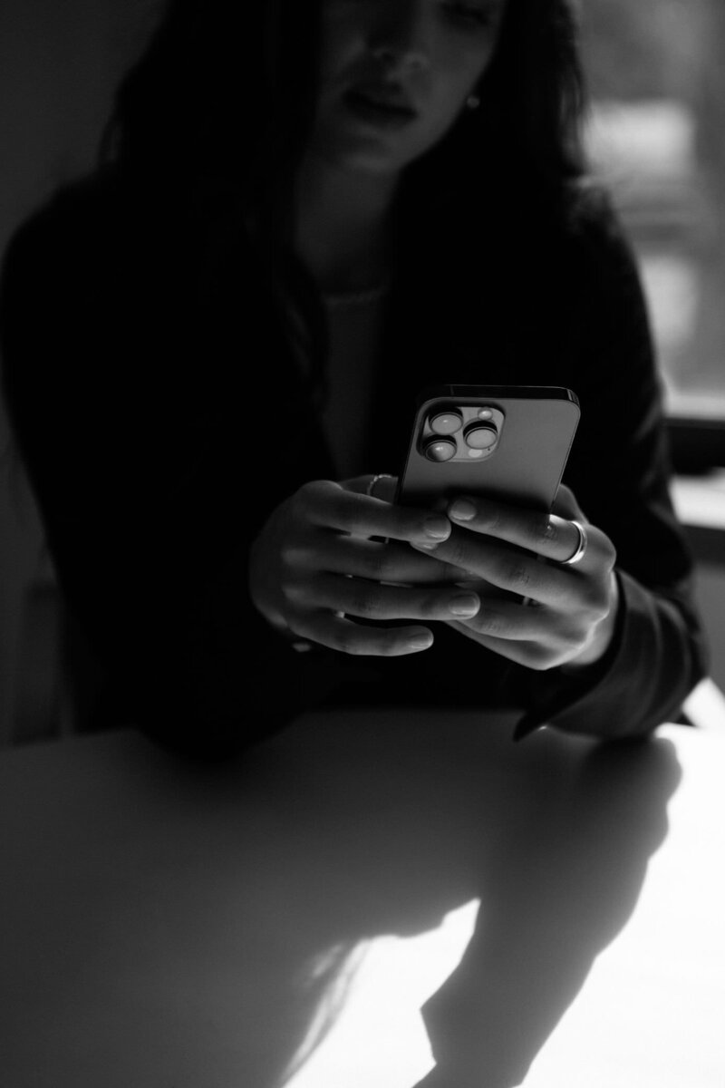 B&W image of a woman holding a phone, representing connection through online mindset coaching.