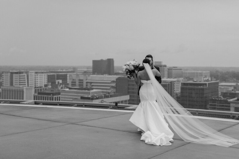 A wedding couple standing on a rooftop kissing 