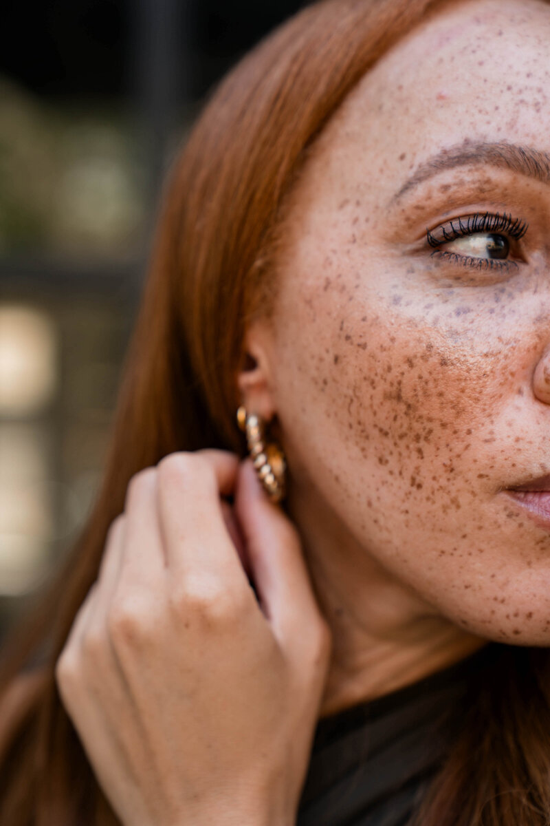 Freckled woman touching her ear
