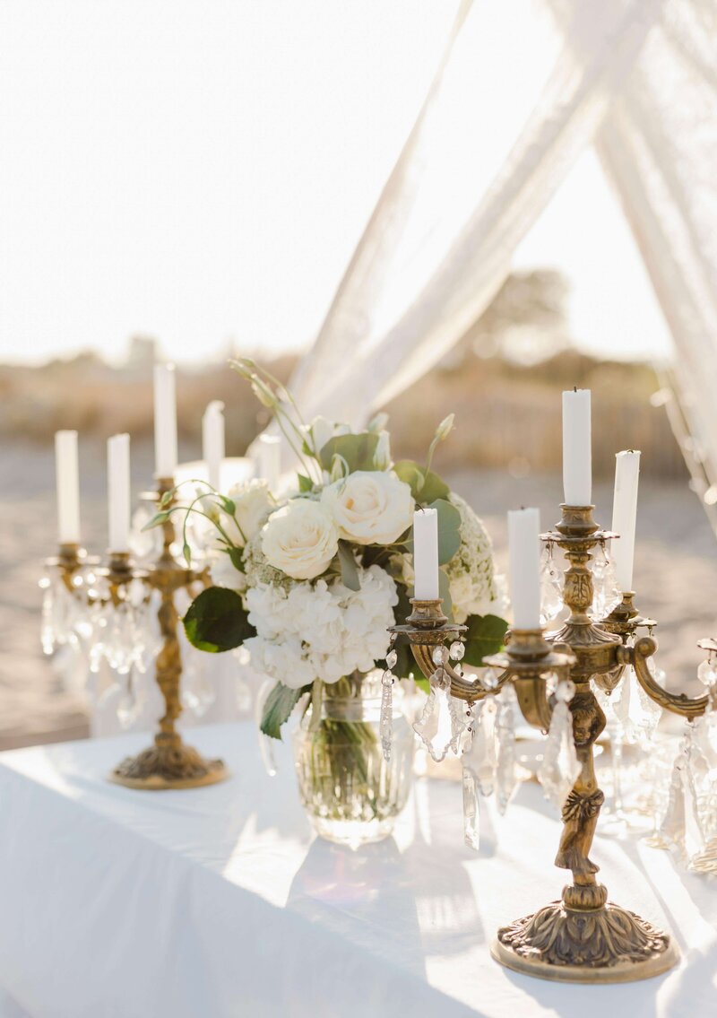 Beautiful beach wedding tablescape with flowers, candelabras, and crystals