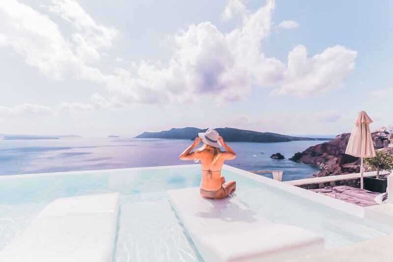 Woman sitting in a pool with view of the ocean, planned by travel concierge GG Mack