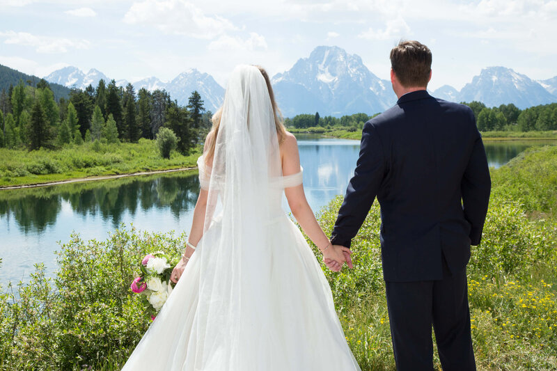 A newlywed bride and groom gaze in awe of Mount Moran at Oxbow Bend in Grand Teton National Park before their Jackson Hole Wedding Reception at Diamond Cross Ranch.