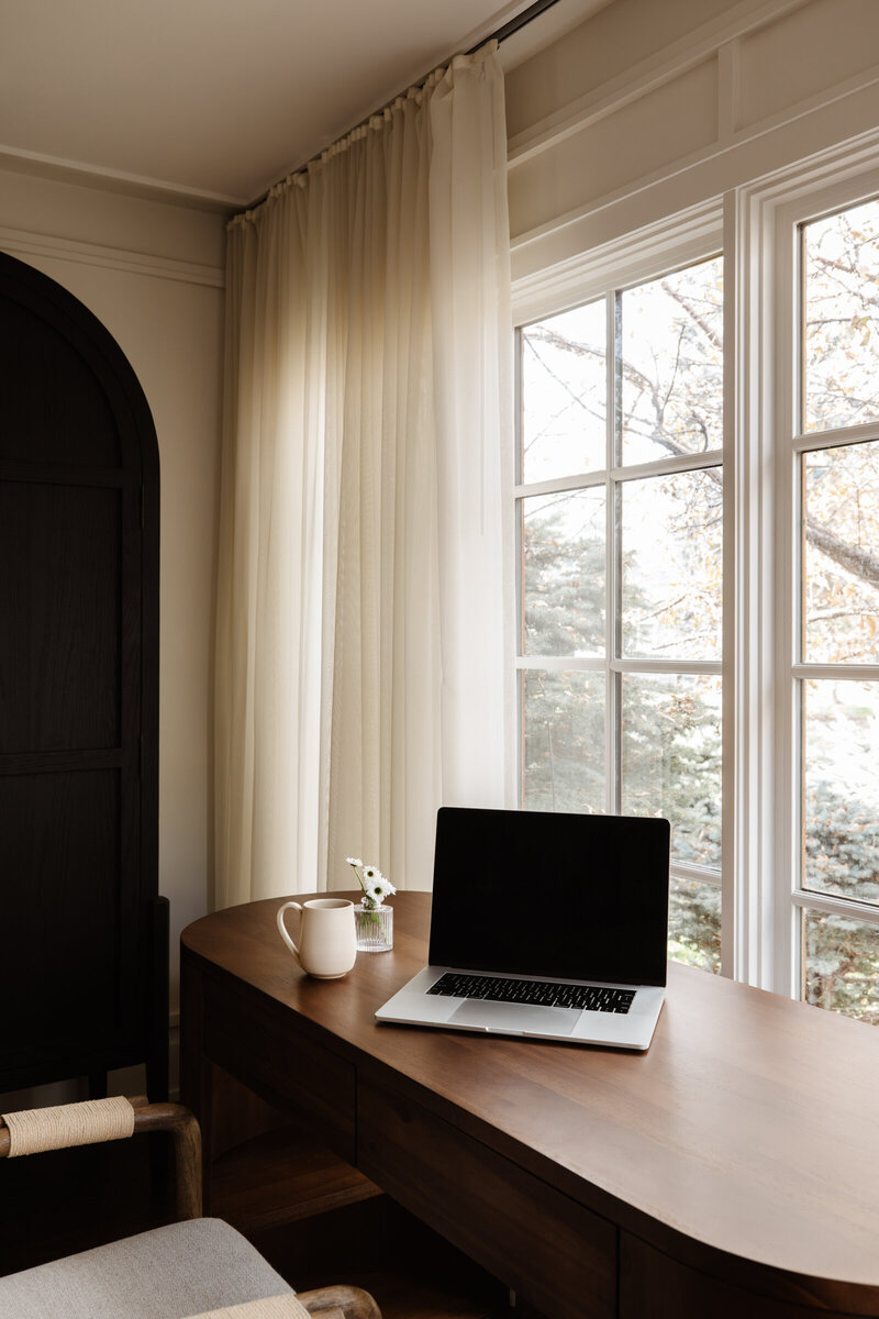 brown wood desk with laptop and coffee mug in neutral setting
