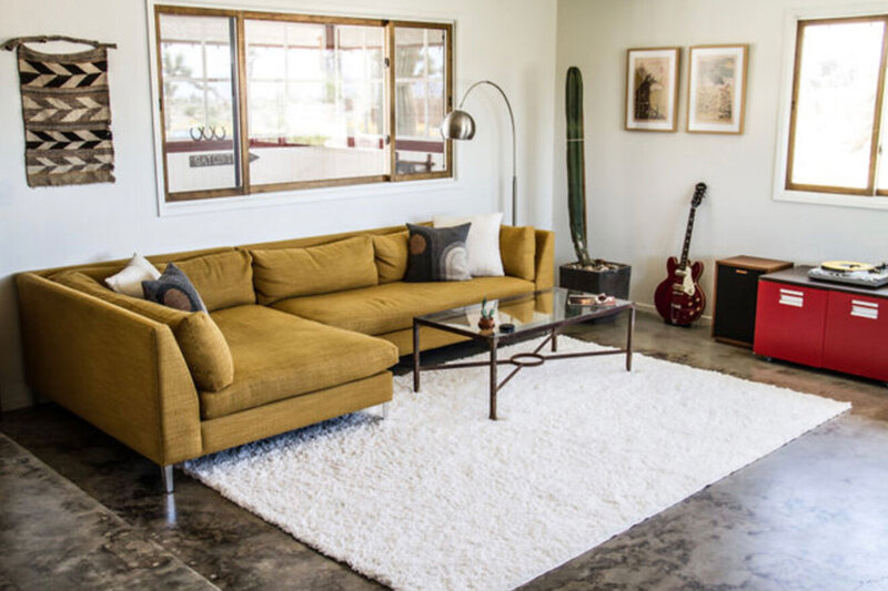 Branding photo Gatos Trail Studio living room with sofa windows and guitar in corner of room