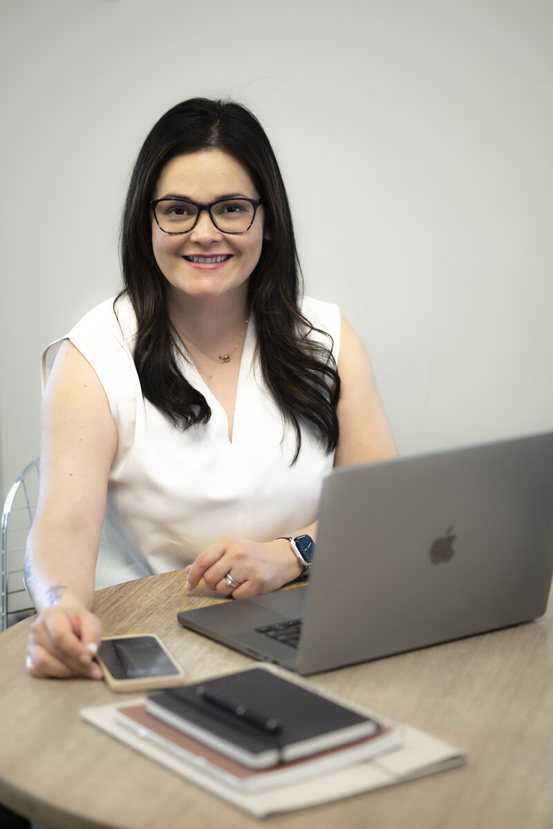 Luisa Kidwell smiling at laptop in white t-shirt – Career and Communication Coach at Kidwell Coaching and Consulting 3