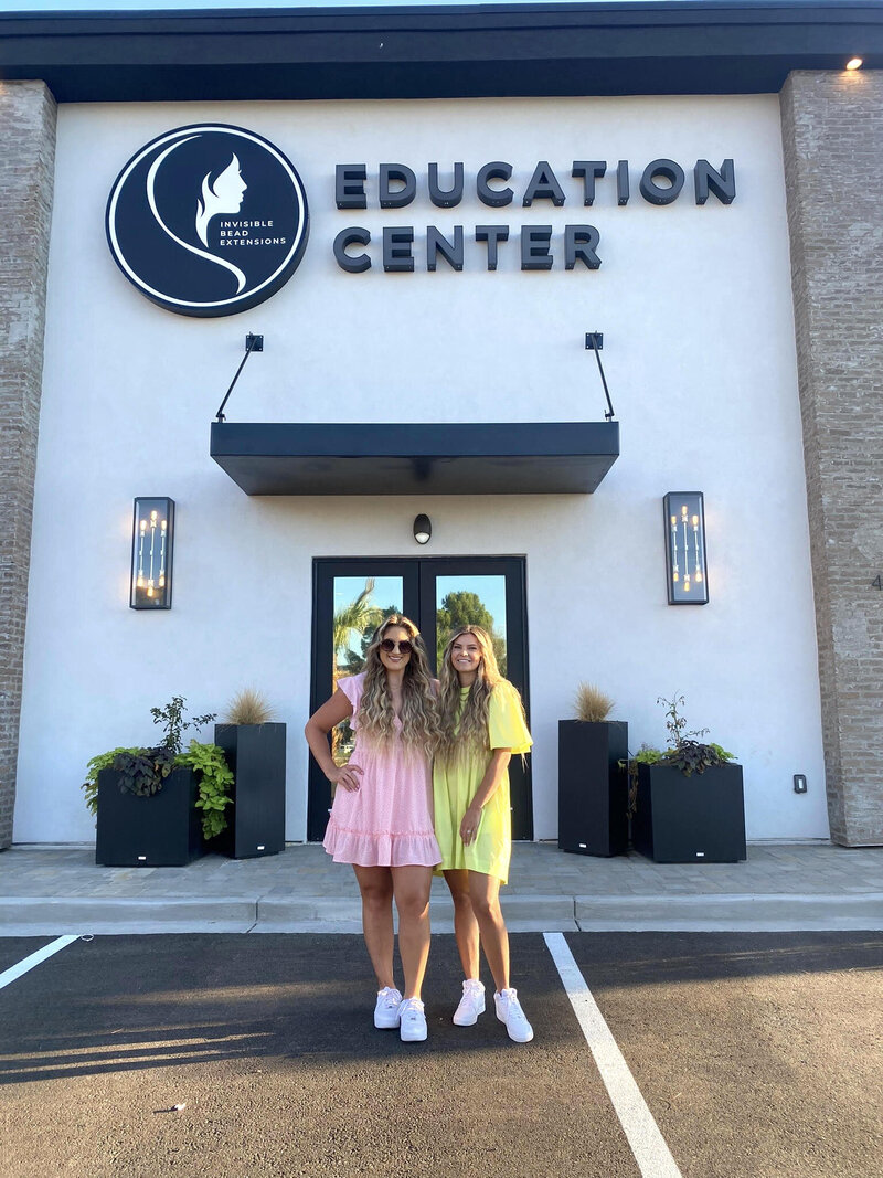 Two hair extensions stylists standing and posing outside of the Invisible Bead Extensions® Education Center