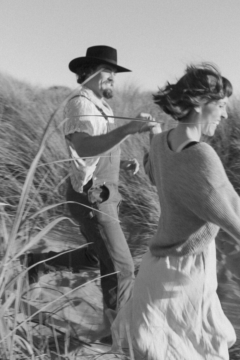 playful engagement photos in oceanside california with couple running and playing in the sand